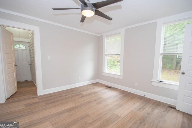 spare room with crown molding, baseboards, ceiling fan, and light wood finished floors