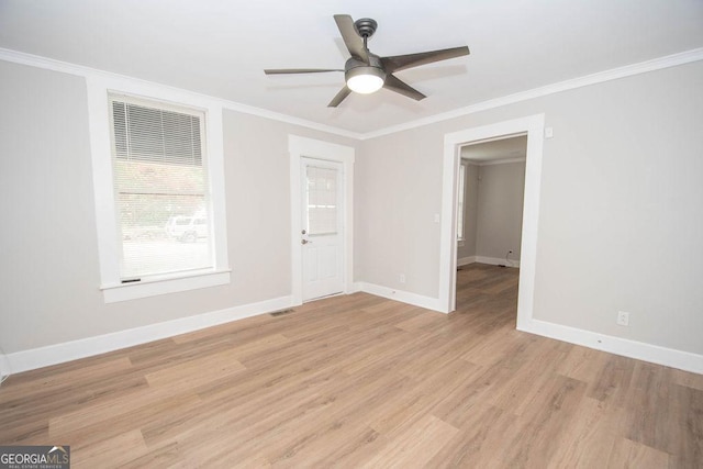 empty room featuring a ceiling fan, baseboards, light wood-type flooring, visible vents, and ornamental molding