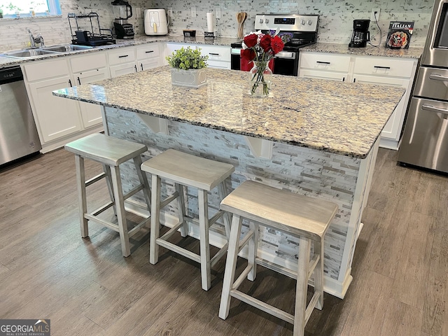 517 Starbuck Pkwy, Pendergrass, GA 30567 - kitchen with appliances with stainless steel finishes, a sink, light wood-style flooring, backsplash, and white cabinetry