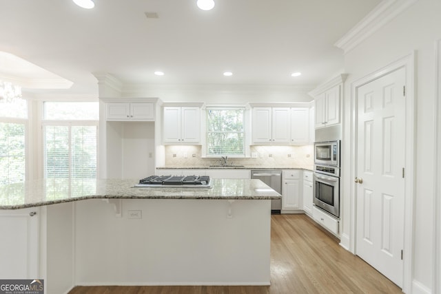 5685 Commons Ln, Alpharetta, GA 30005 - kitchen with a kitchen breakfast bar, crown molding, appliances with stainless steel finishes, a sink, and white cabinetry