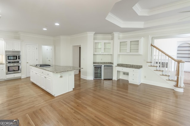 5685 Commons Ln, Alpharetta, GA 30005 - kitchen with a kitchen island, appliances with stainless steel finishes, white cabinets, wine cooler, and light wood-style flooring