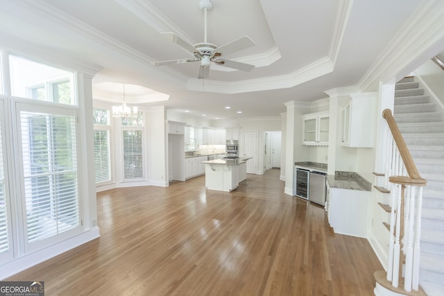 5685 Commons Ln, Alpharetta, GA 30005 - unfurnished living room with wine cooler, a raised ceiling, ceiling fan with notable chandelier, and light wood-style flooring