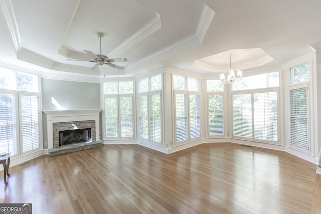 5685 Commons Ln, Alpharetta, GA 30005 - unfurnished living room with a stone fireplace, crown molding, a raised ceiling, ceiling fan with notable chandelier, and light wood-style floors