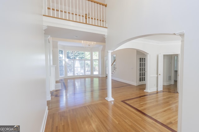 5685 Commons Ln, Alpharetta, GA 30005 - unfurnished living room with ornamental molding, wood finished floors, baseboards, stairway, and arched walkways