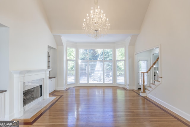 5685 Commons Ln, Alpharetta, GA 30005 - unfurnished living room with an inviting chandelier, a high end fireplace, wood finished floors, and stairway