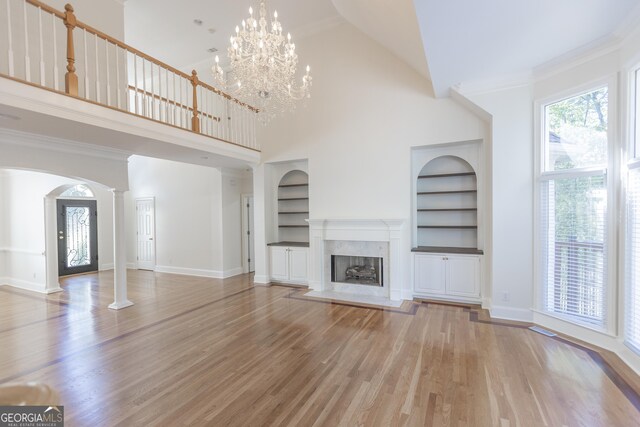 5685 Commons Ln, Alpharetta, GA 30005 - unfurnished living room with baseboards, arched walkways, wood finished floors, and built in shelves