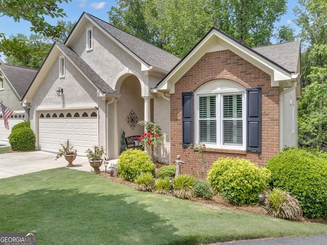 ranch-style house featuring driveway, brick siding, a front lawn, an attached garage, and stucco siding