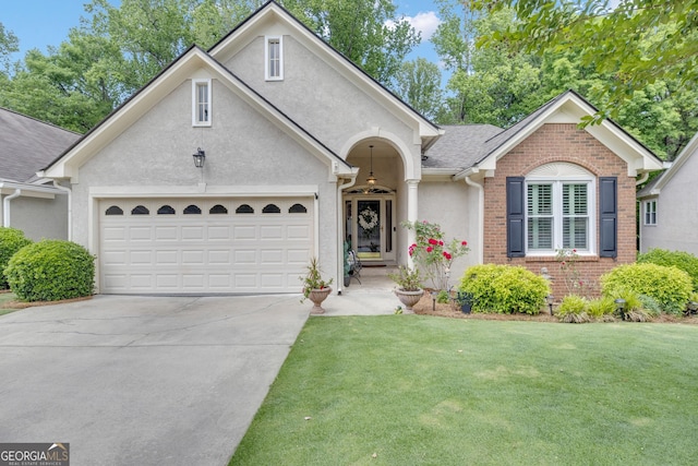 view of front of property with a front lawn, brick siding, a garage, stucco siding, and driveway