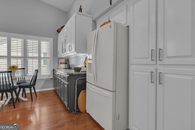 kitchen with white cabinets, white refrigerator with ice dispenser, and wood finished floors