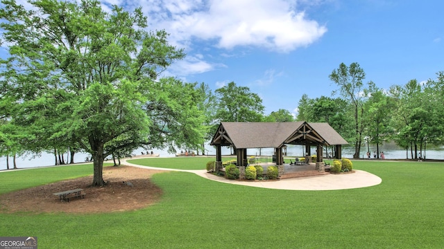 view of property's community with a gazebo, a water view, and a lawn