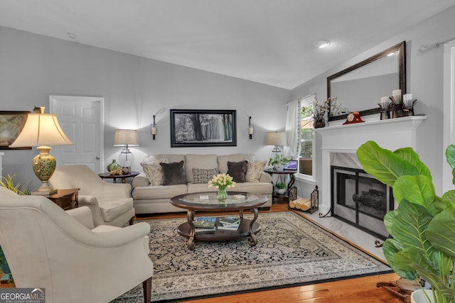 living area featuring a high end fireplace, wood finished floors, and lofted ceiling