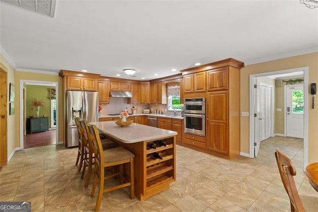 122 Gold View Dr, Dahlonega, GA 30533 - kitchen featuring stainless steel appliances, under cabinet range hood, light countertops, brown cabinets, and ornamental molding