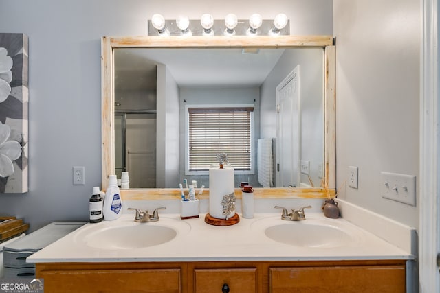 full bathroom with double vanity, a sink, and a shower with shower door