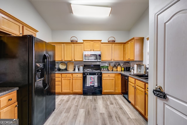 kitchen with a sink, black appliances, and light wood-type flooring