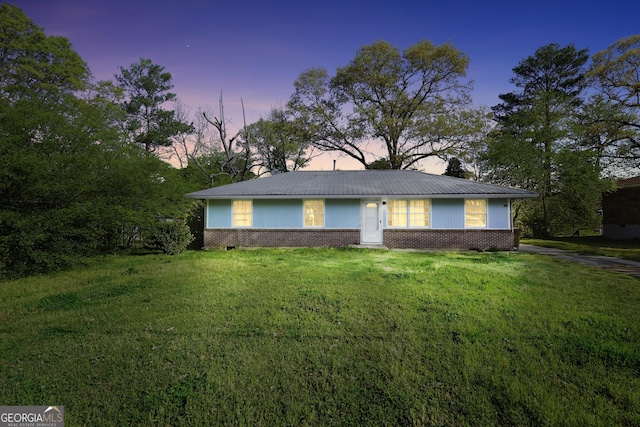 single story home featuring a front yard, metal roof, and brick siding