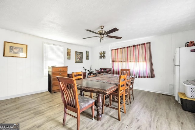 dining space featuring baseboards, ceiling fan, and light wood finished floors