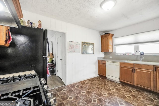 kitchen with freestanding refrigerator, light countertops, a sink, dishwasher, and gas stove