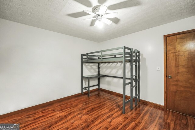 175 Laney Ct, Mcdonough, GA 30252 - unfurnished bedroom with baseboards, a textured ceiling, and wood finished floors