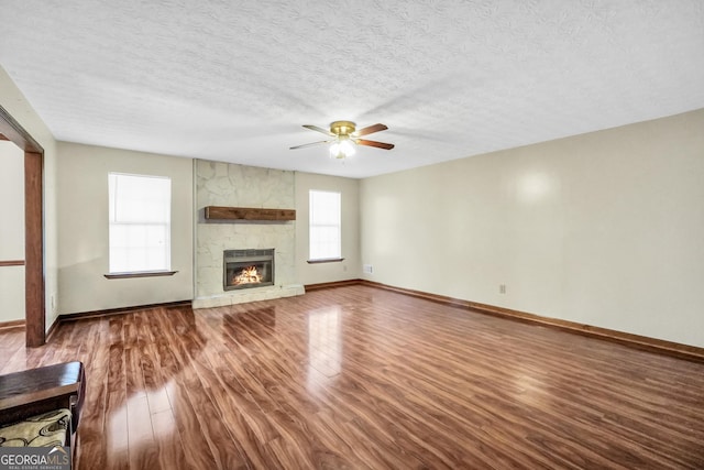175 Laney Ct, Mcdonough, GA 30252 - unfurnished living room with wood finished floors, a fireplace, baseboards, ceiling fan, and a textured ceiling