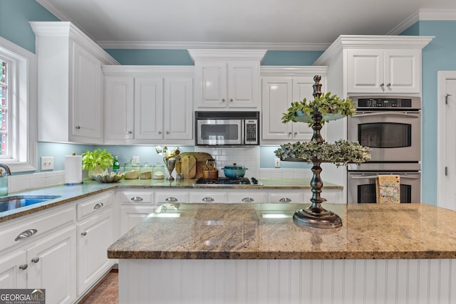 kitchen featuring a sink, white cabinets, light stone countertops, and stainless steel appliances