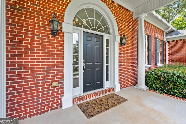 entrance to property featuring a porch and brick siding