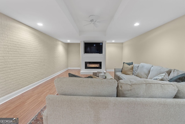 living room with a ceiling fan, baseboards, a large fireplace, and wood finished floors