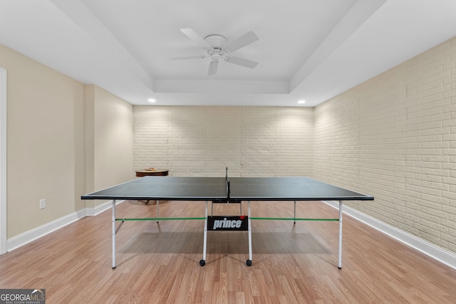 playroom with baseboards, ceiling fan, wood finished floors, and a raised ceiling