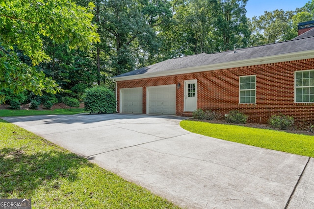 view of home's exterior featuring a shingled roof, brick siding, a garage, a lawn, and driveway