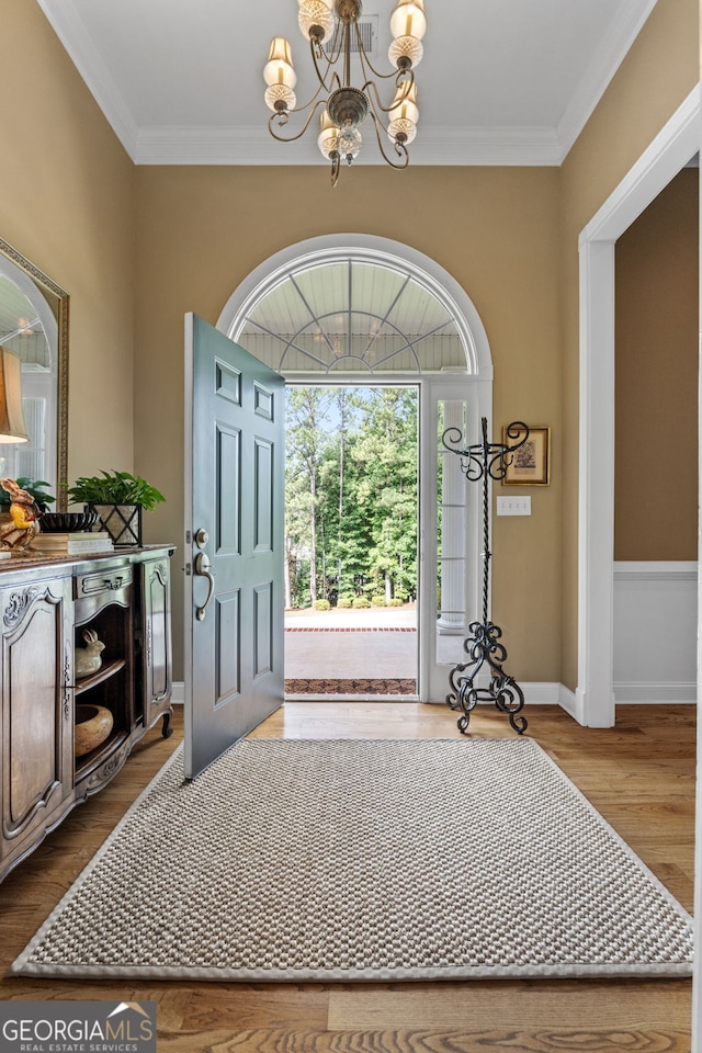 entrance foyer featuring baseboards, crown molding, wood finished floors, and a chandelier