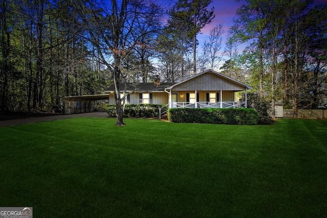 view of front of home with a porch, a lawn, aphalt driveway, and a carport