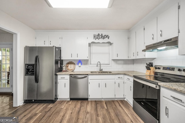 kitchen with decorative backsplash, appliances with stainless steel finishes, dark wood finished floors, a sink, and under cabinet range hood