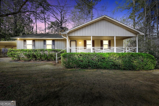 view of front of property with covered porch, a chimney, and a front yard