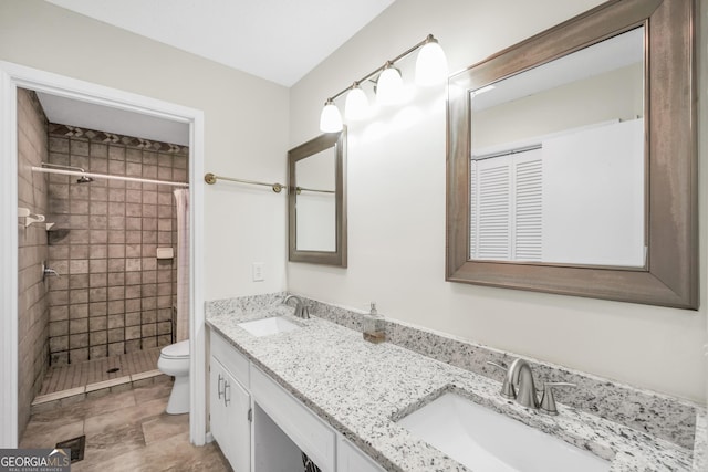 full bathroom with a sink, double vanity, toilet, and tiled shower