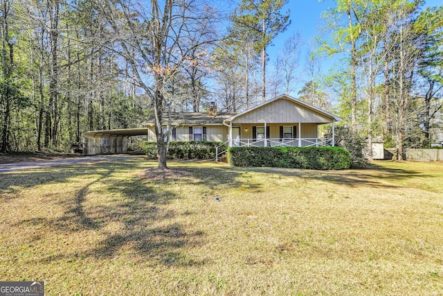 view of front of house with a porch, driveway, a chimney, a carport, and a front lawn