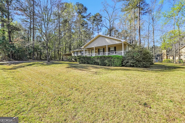 view of side of home with a lawn, board and batten siding, and a porch