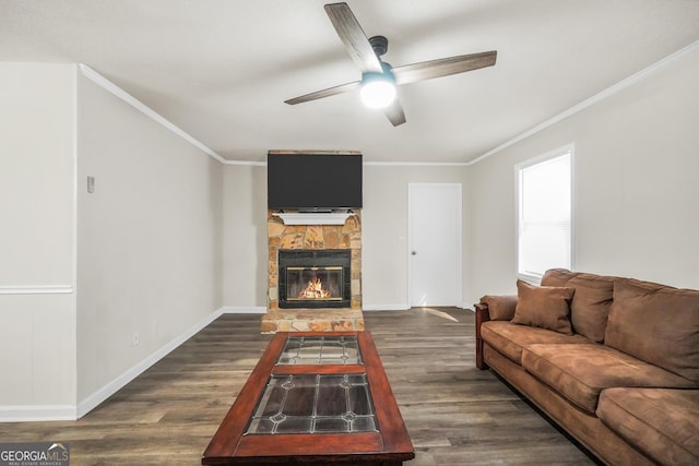 living area featuring ceiling fan, ornamental molding, dark wood finished floors, and a stone fireplace