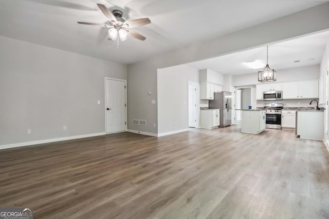 1931 Abinger Way, Lawrenceville, GA 30043 - unfurnished living room featuring a ceiling fan, baseboards, visible vents, and wood finished floors