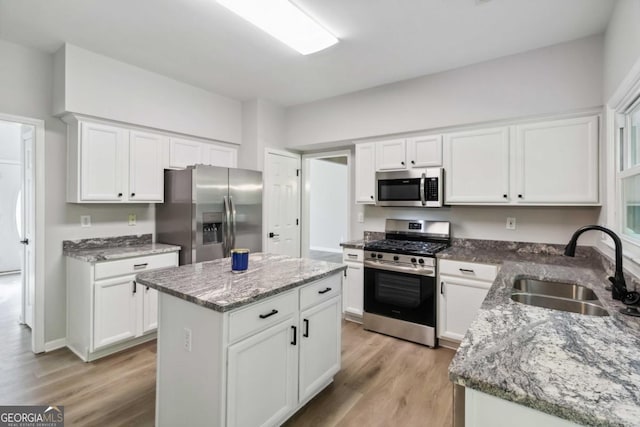 1931 Abinger Way, Lawrenceville, GA 30043 - kitchen featuring stainless steel appliances, light wood-type flooring, white cabinets, a center island, and light stone counters