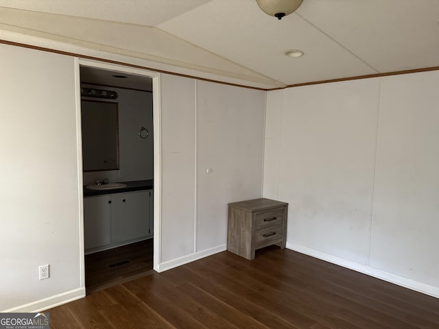 unfurnished bedroom with visible vents, lofted ceiling, baseboards, dark wood-type flooring, and a sink