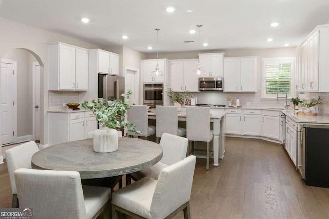 kitchen with backsplash, a center island, a sink, stainless steel appliances, and white cabinetry
