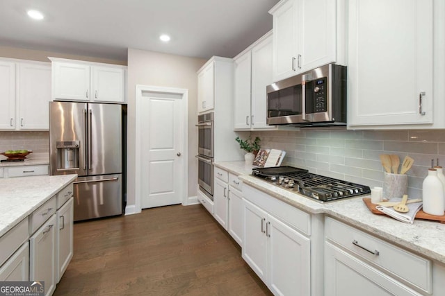kitchen with white cabinets, appliances with stainless steel finishes, dark wood-style floors, and tasteful backsplash