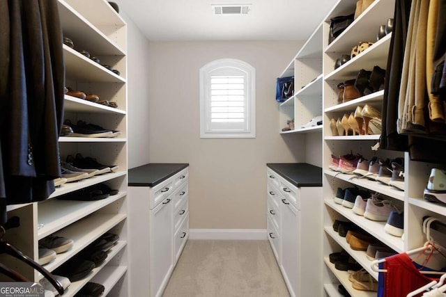 walk in closet featuring visible vents and light carpet