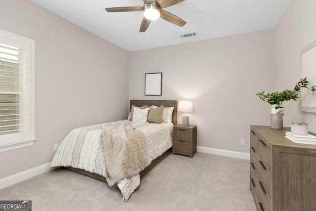 bedroom with visible vents, baseboards, multiple windows, and light carpet