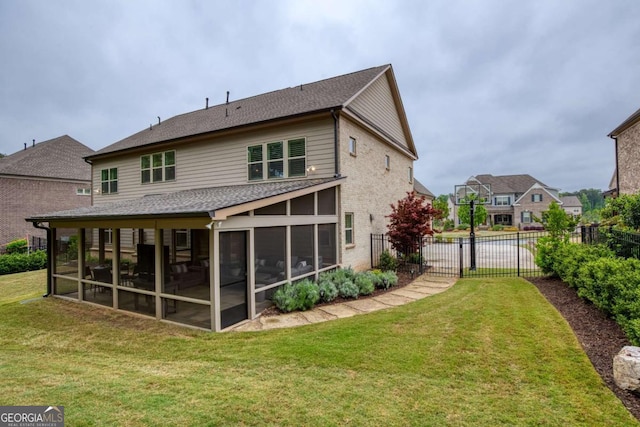 rear view of house featuring a sunroom, a shingled roof, fence, and a yard