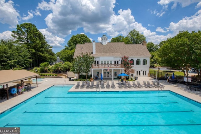 community pool with french doors, fence, and a patio area