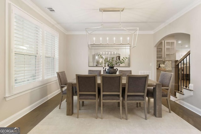 dining space with visible vents, ornamental molding, and wood finished floors