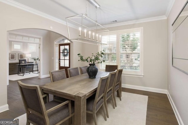 dining area featuring ornamental molding, wood finished floors, baseboards, a chandelier, and arched walkways