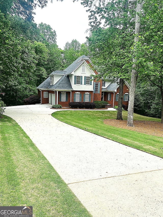 view of front of property featuring brick siding, driveway, a front yard, and a garage