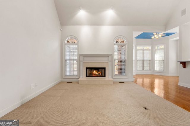 unfurnished living room with carpet flooring, a fireplace, baseboards, lofted ceiling, and visible vents