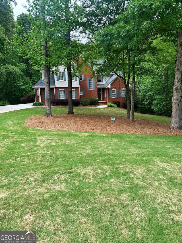 view of front facade featuring concrete driveway, brick siding, and a front yard